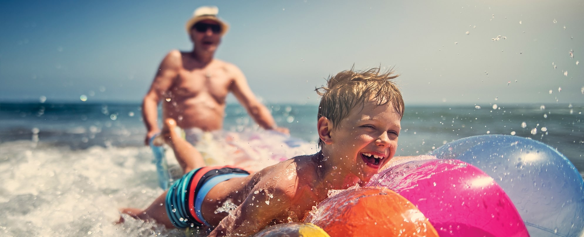 A father and son play with a pool float in the ocean while on a beach vacation during spring break